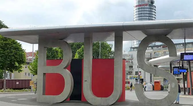 Große Buchstaben 'BUS' an einer modernen Bushaltestelle in einer städtischen Umgebung.