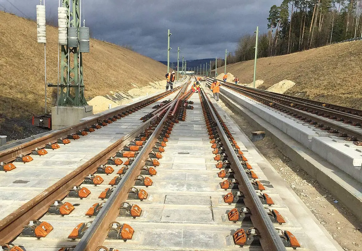 Gleisbau mit mehreren Schienen und Schwellen auf einer Baustelle im Freien.