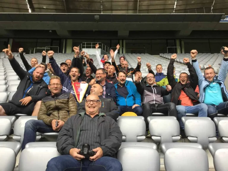 Gruppe von Menschen im Stadion, die mit Fanfaren und jubelnden Gesten posieren.