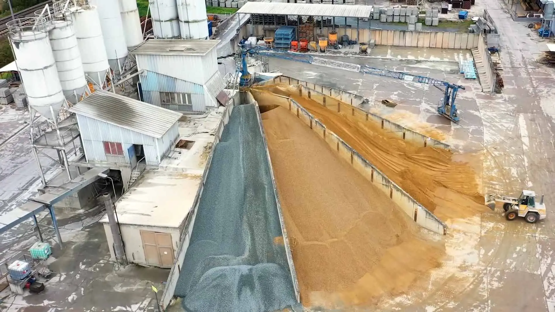 Luftaufnahme eines Lagerbereichs mit verschiedenen Materialien wie Sand und Kies.